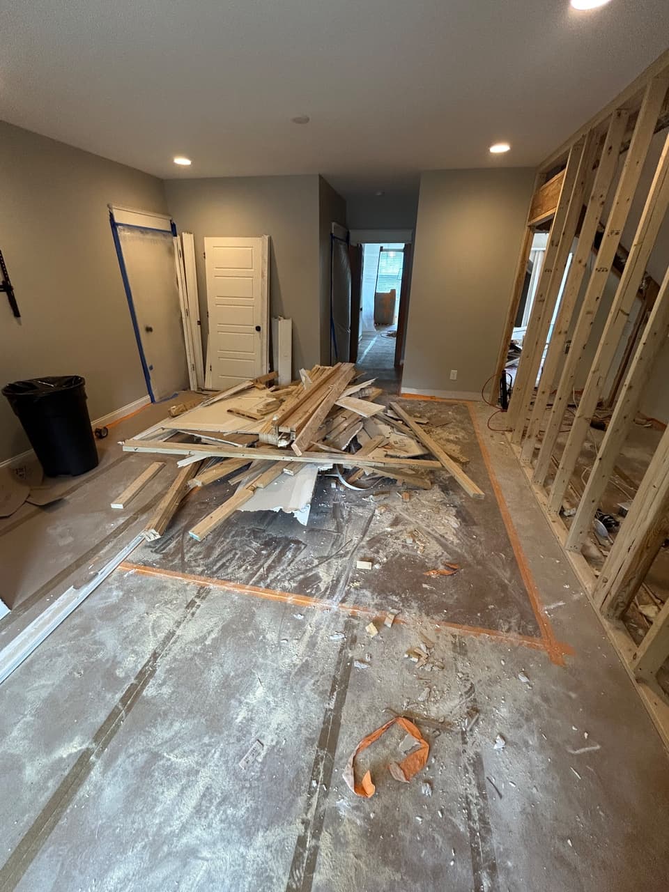 Light demolition — interior wall framing torn out with lumber and debris piled for haul-off